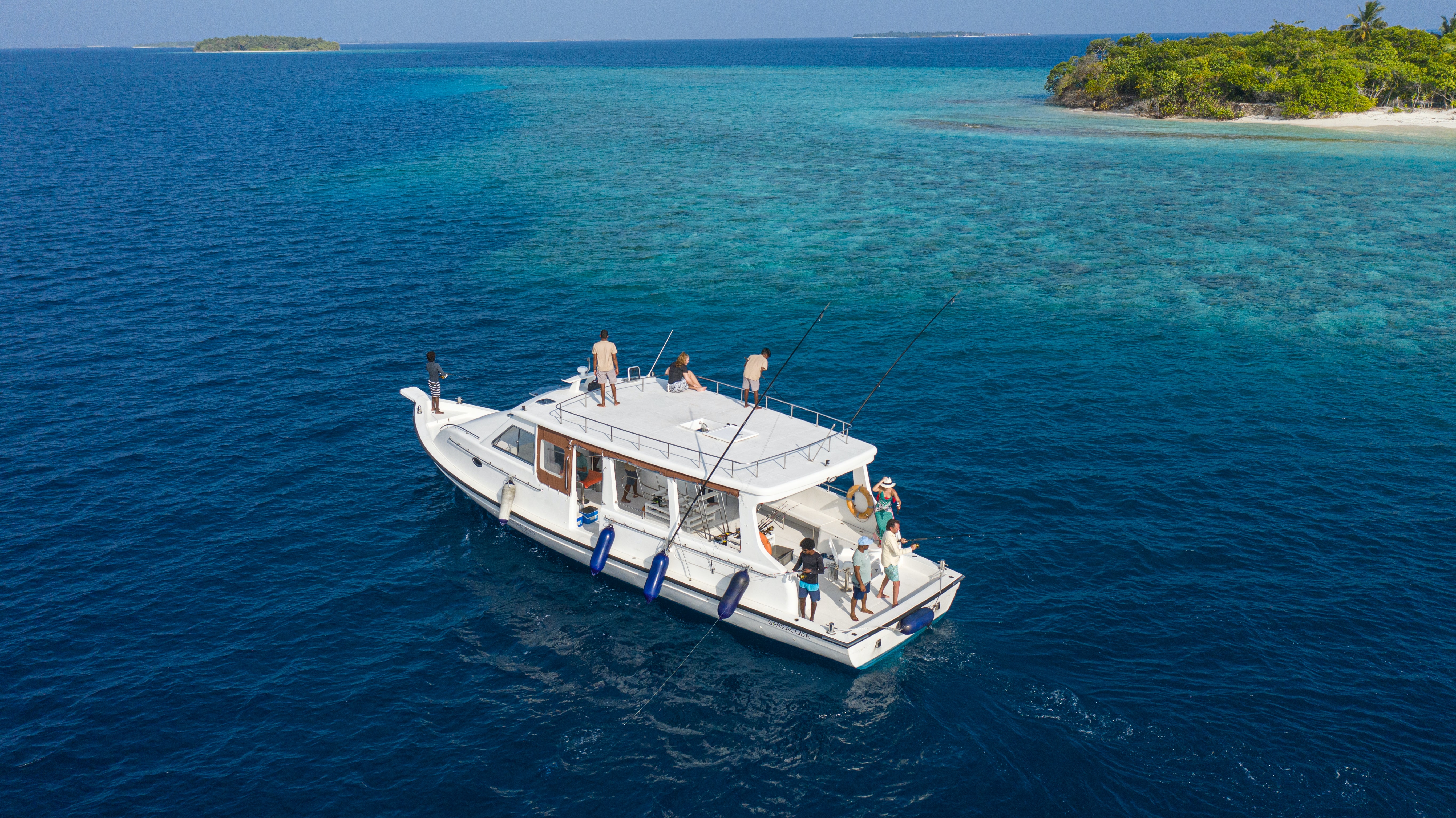 Boat with people on open blue water near a small island.